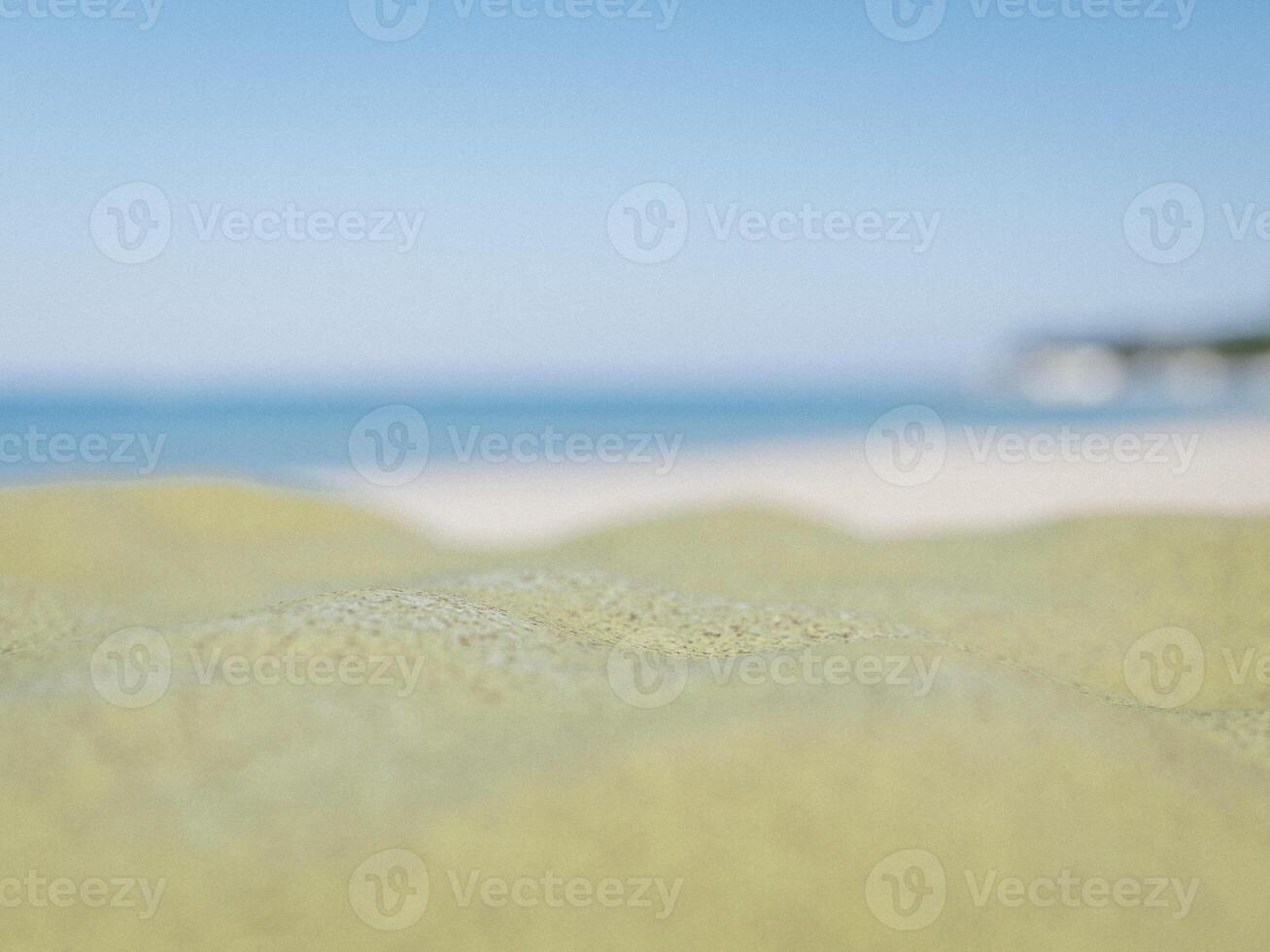 Sandy beach close-up with the blurred blue ocean and cloudy sky. photo