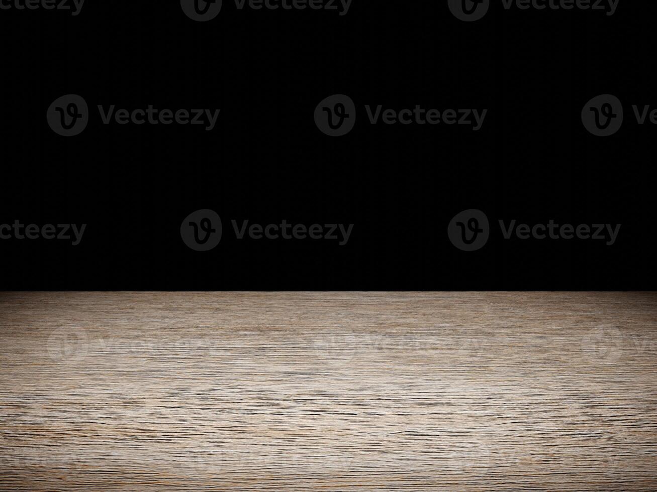 Softly illuminated wood table showcasing its texture, contrasted by a deep black background. photo