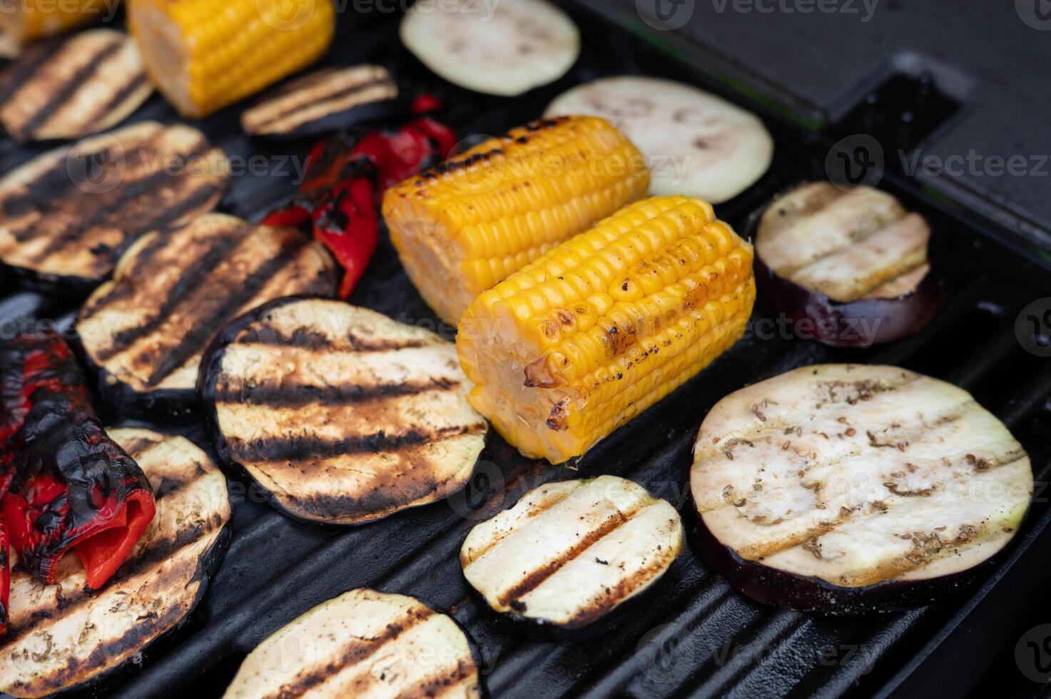 Grilled vegetables on barbecue including corn, eggplant, and bell peppers photo