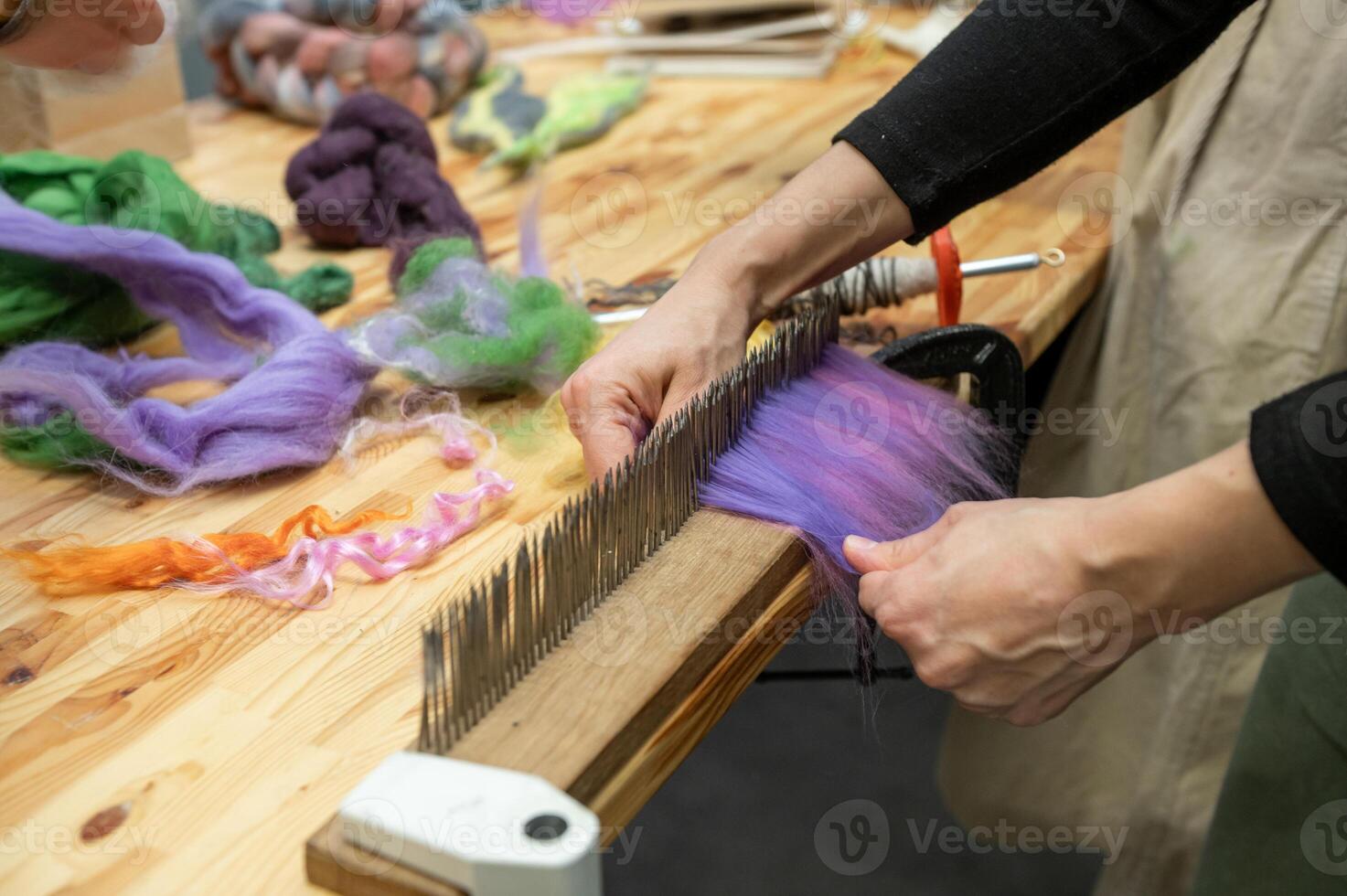 Hands preparing wool for crafting on hackle with colorful fibers photo