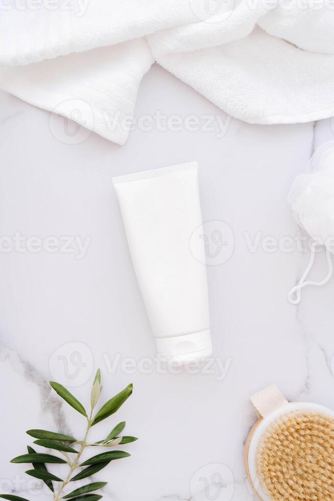 Flat lay of plastic bottle without label, wooden brush, sponge for body and towel on white bath marble background photo