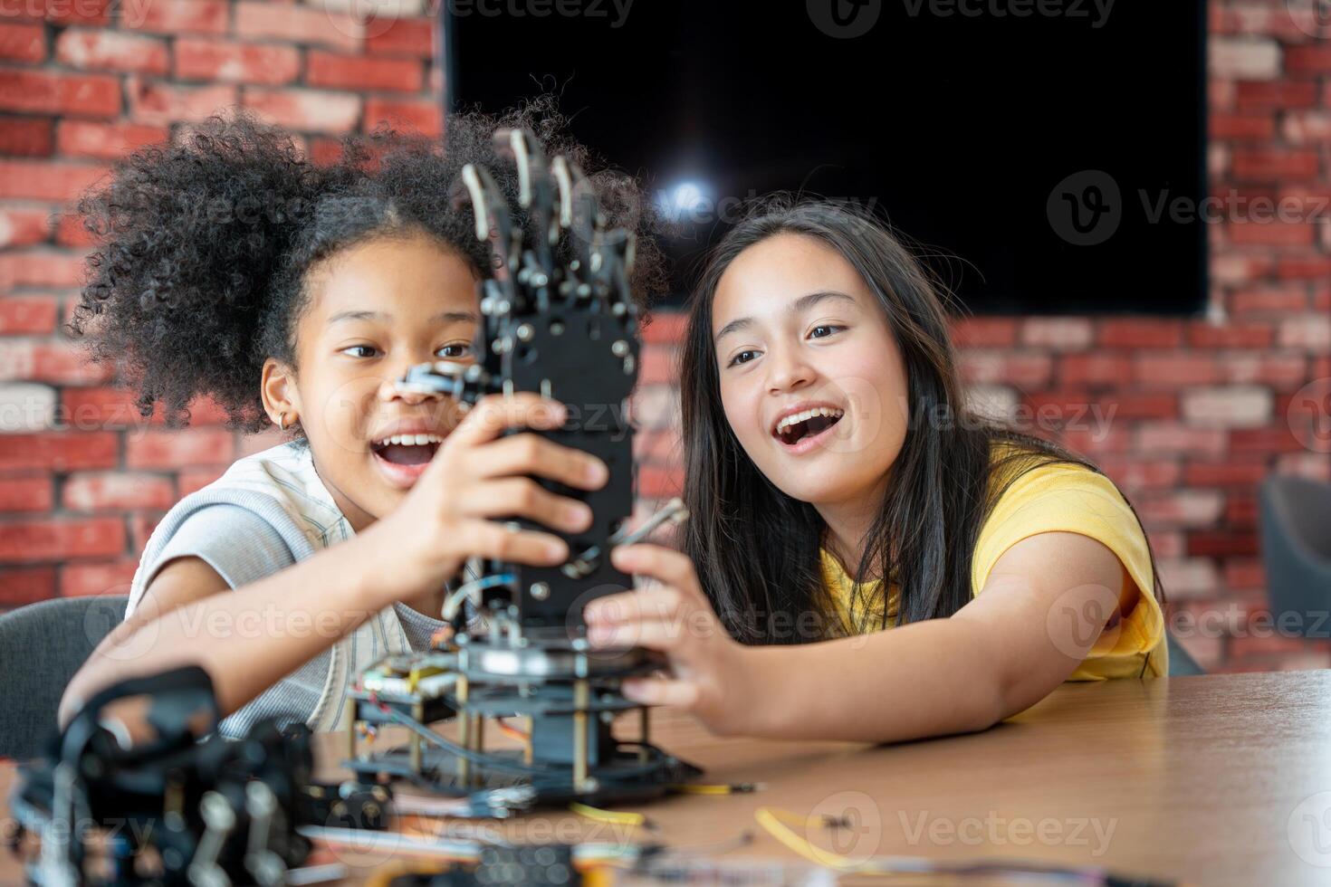 Children Learning Robotics, Young Girls Engaged in Robotics and STEM Learning, Diverse Kids Building a Robot Arm in a Science Workshop, Two Girls Exploring Technology and Innovation photo