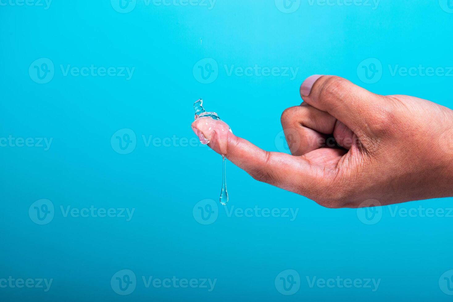 Gel droplet on a finger and light blue background. photo