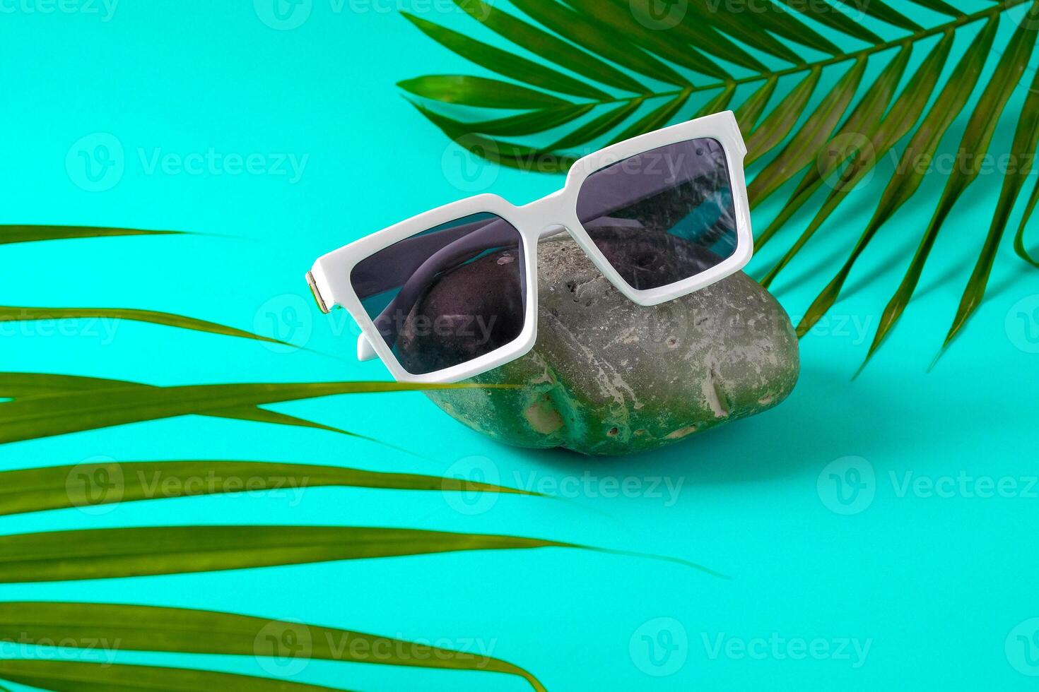 Sunglasses on rock with palm photo