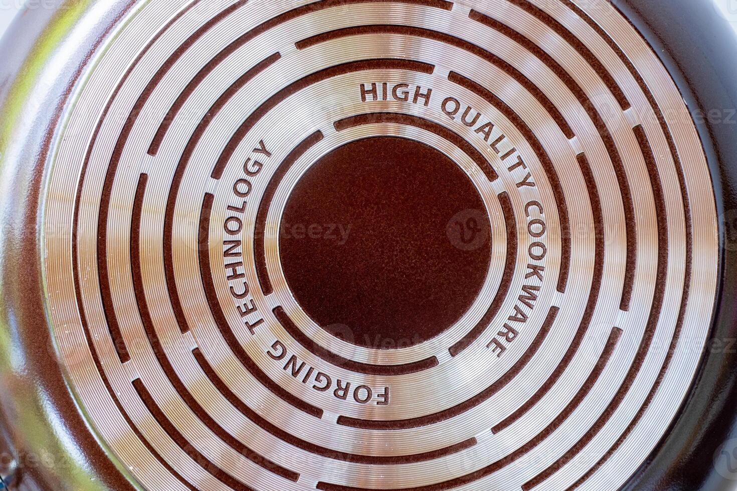 Close up of the bottom surface of a high quality non stick frying pan with engraved text and concentric metal rings. Concept for modern kitchenware, durable cookware, and cooking technology photo