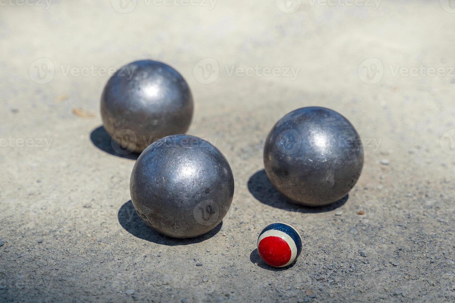 Petanque balls are placed near a target ball on an outdoor dirt field photo