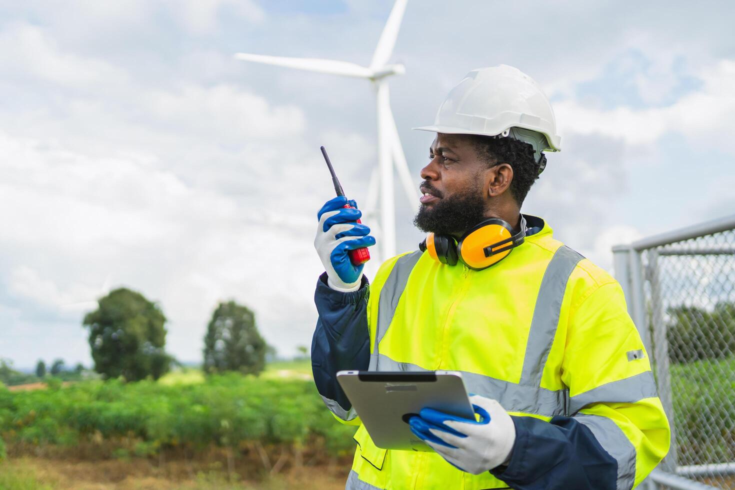 man in a yellow safety vest is holding a walkie talkie and a tablet photo
