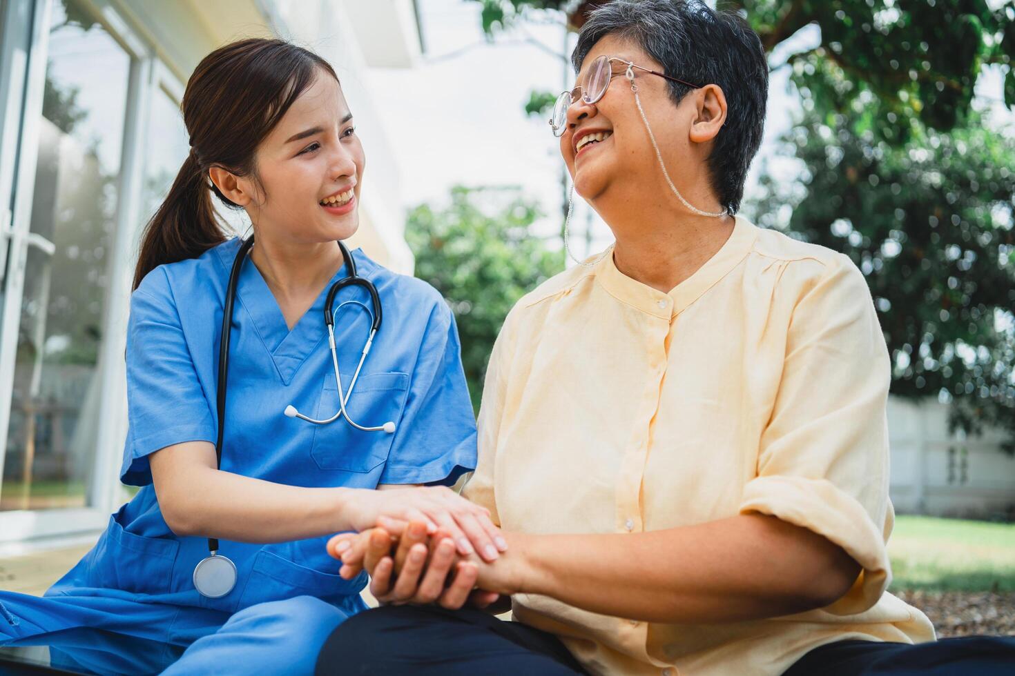 woman in a blue uniform is holding hands with an older woman in a yellow shirt photo