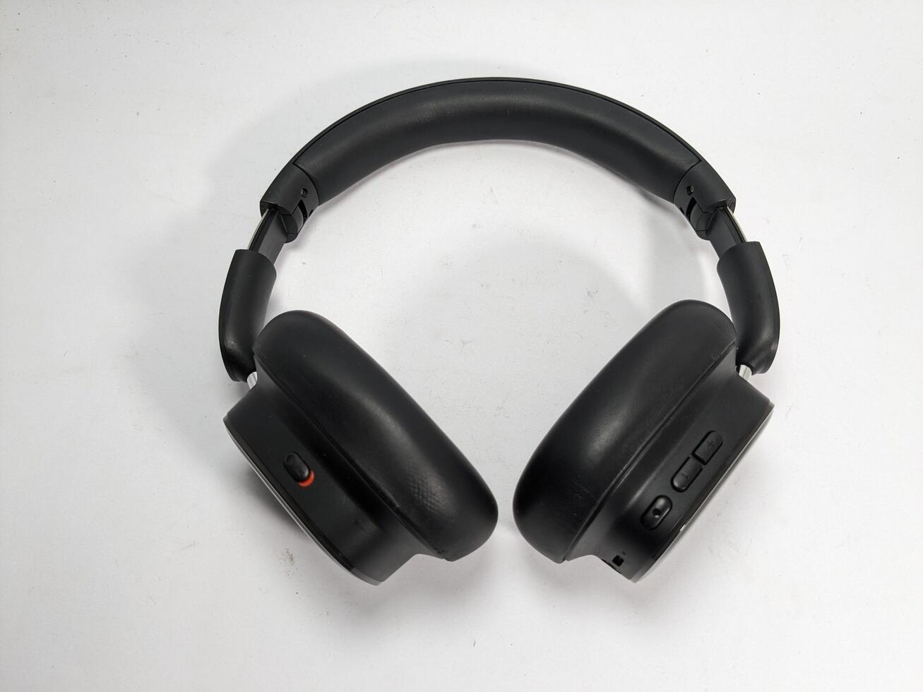 Overhead shot of modern black wireless headphones on a white surface background photo