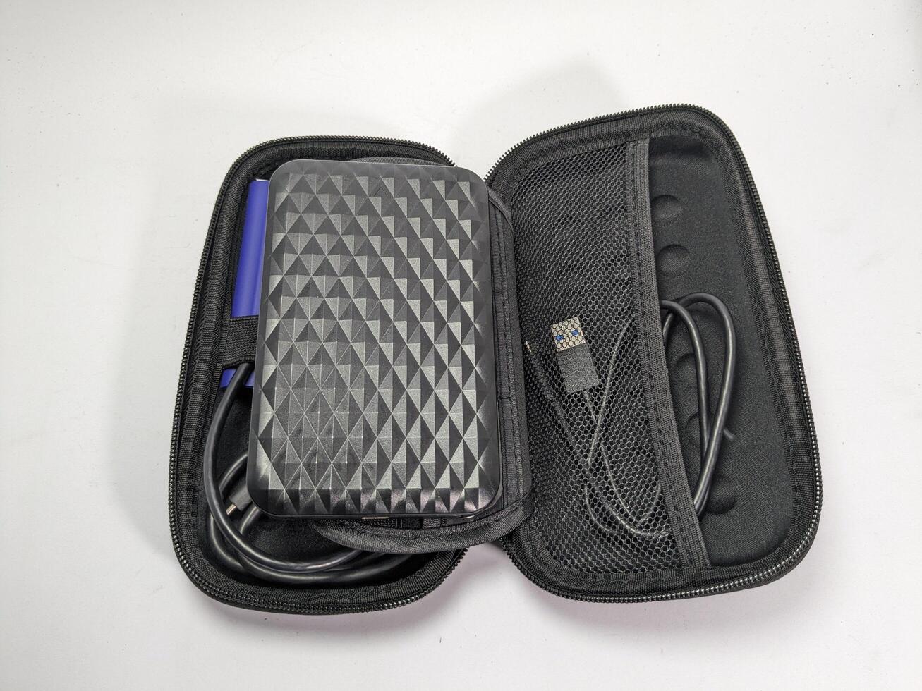 Open Black Case with External Hard Drive, Cable, and Accessories on White Surface photo