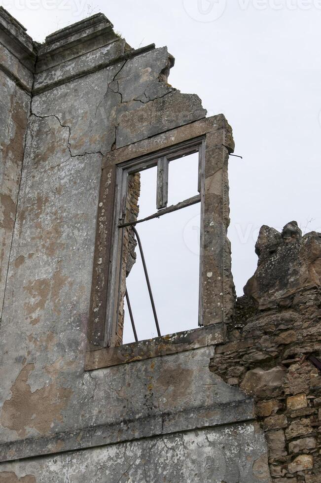 Window in the wall of what is left of a house photo