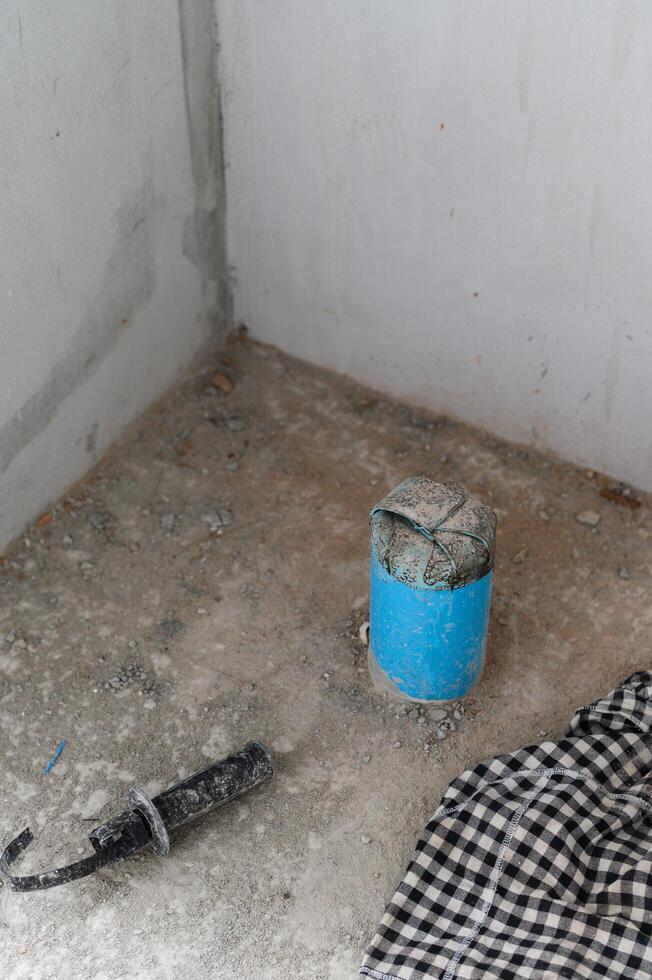 Feeling of progress in messy house renovation. Unfinished concrete floor and wall in corner showing construction detail and capped plumbing pipe awaiting work photo