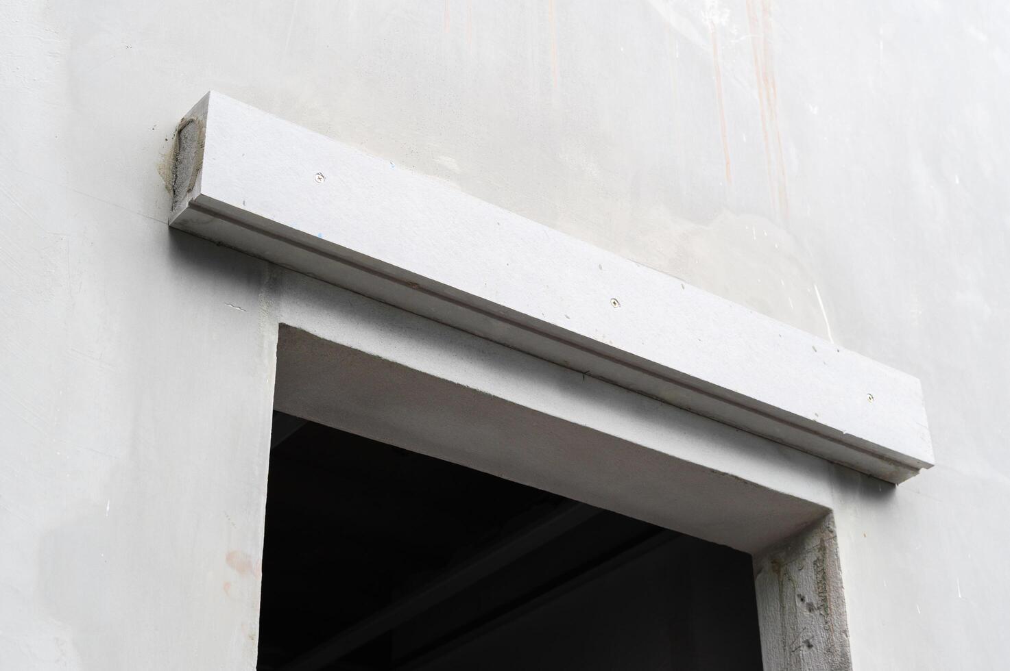 White architectural lintel installation over window opening on concrete wall. Close up detail of building site during thoughtful house renovation and construction photo