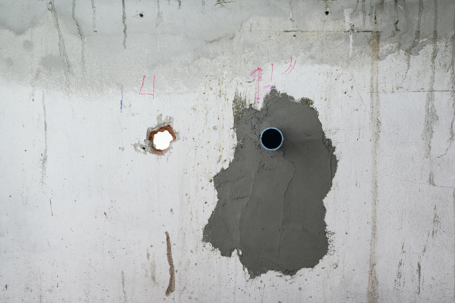 Wet cement patch on concrete wall for pipe repair during house renovation. industrial grunge texture shows an unfinished construction site with plumbing work in progress photo