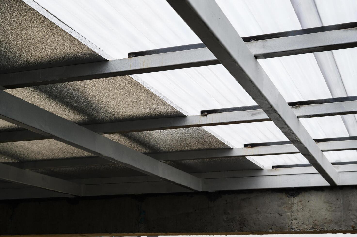 Gray metal framework supports translucent plastic sheet panels. Above insulation resembling foam adds to structure material. Construction potentially includes pu properties for durability photo