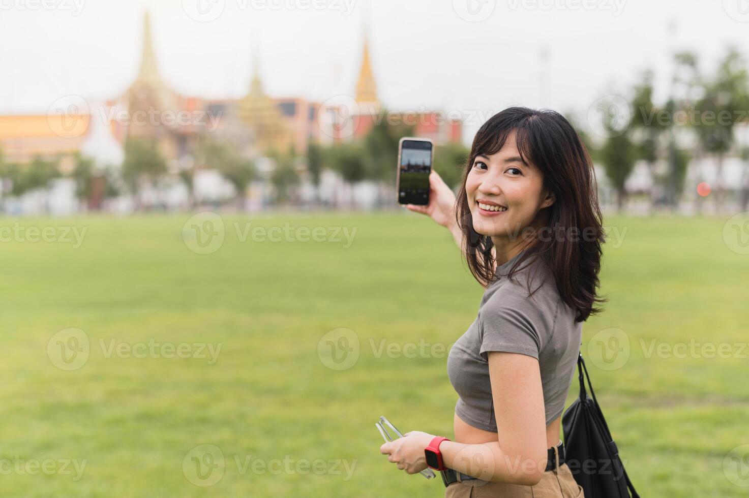 Happy southeast asian woman teenager blogger on solo world travel. An explorer local cultural tourism experience in Bangkok Thailand. Take photo with smartphone. Asia travel concept