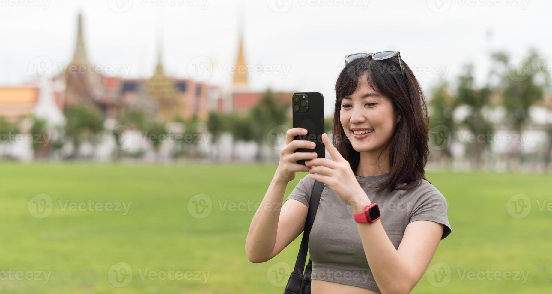 Happy solo Southeast Asian woman teenager blogger and world travel explorer enjoying tourism concept in Asia use smartphone to take photo for local cultural experience in Bangkok Thailand