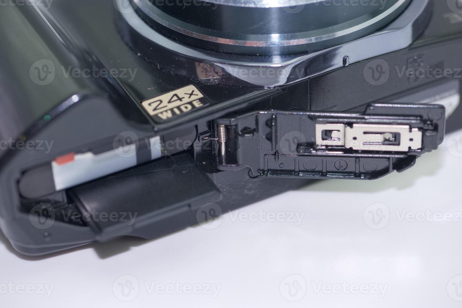 Camera showcasing a 24x wide zoom lens with an open compartment for battery and memory card access photo