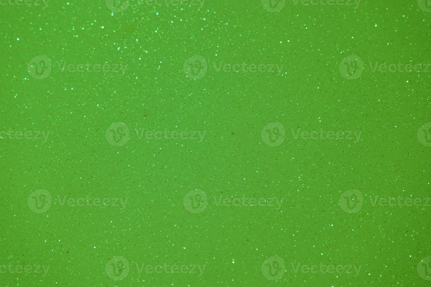 Bright green sparkling surface with tiny glitter particles shining under light photo