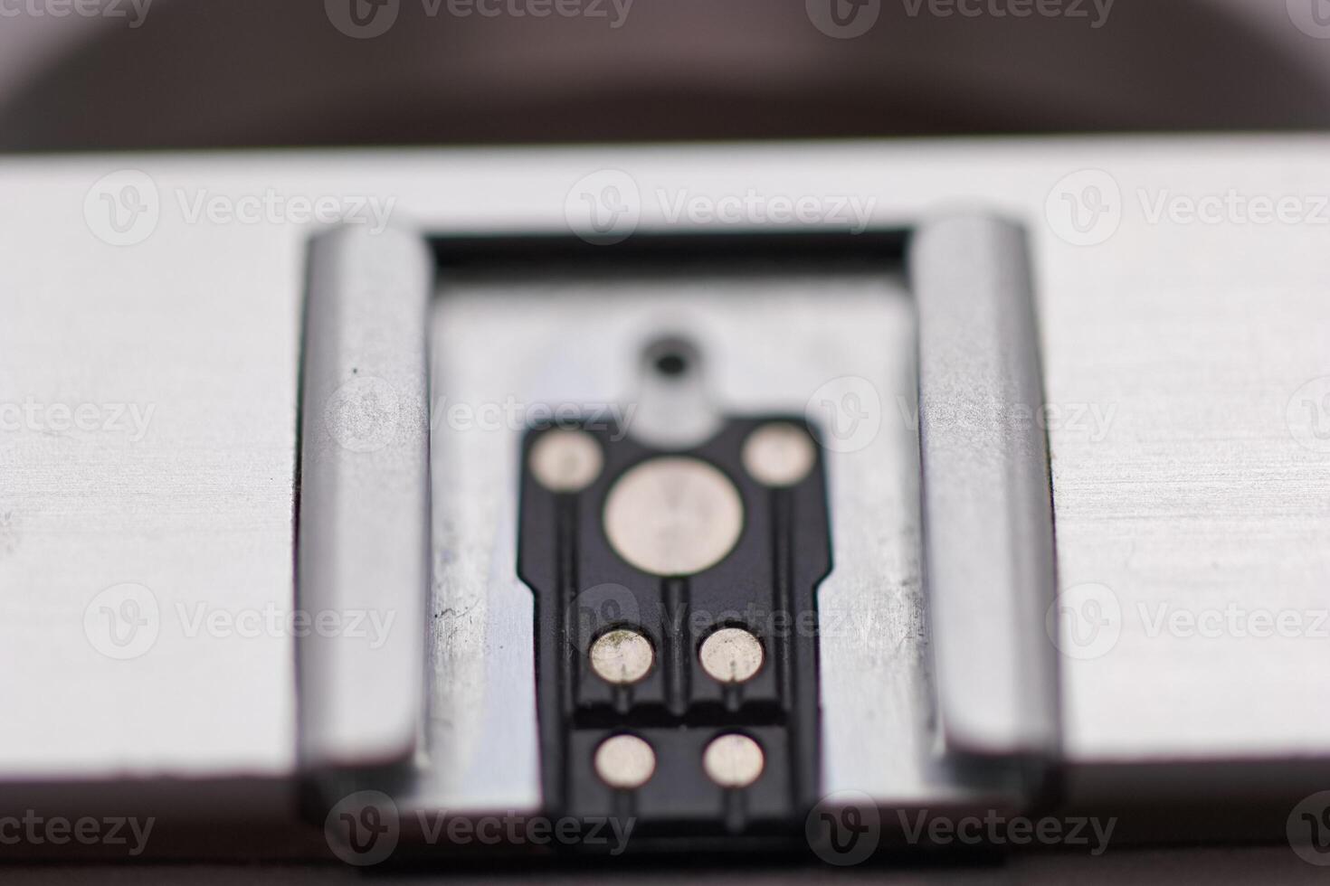 Close up view of a metal component with electrical contacts on a smooth surface in a workshop setting photo