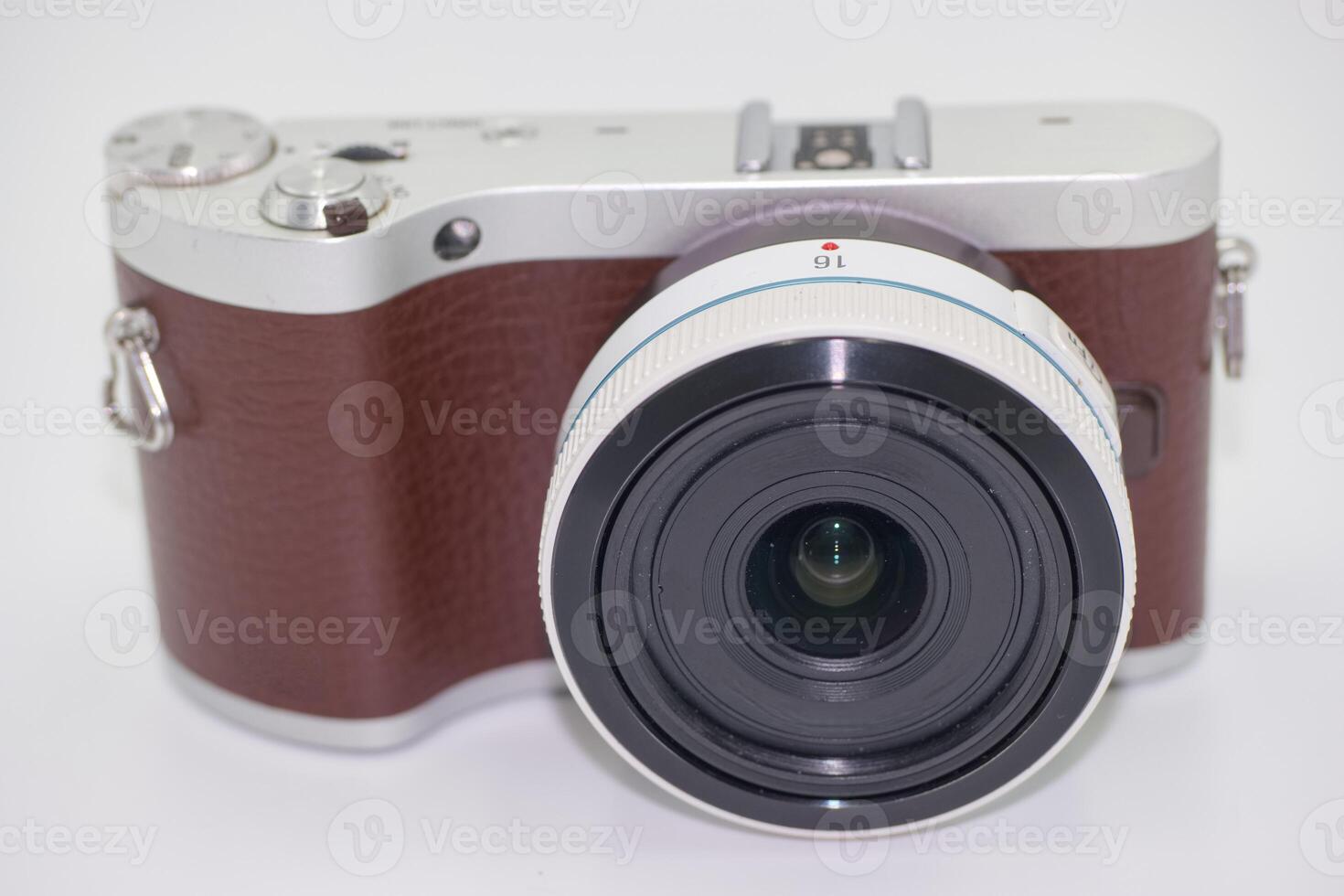 Compact camera with a stylish design featuring a brown leather grip and wide angle lens on a clean background photo