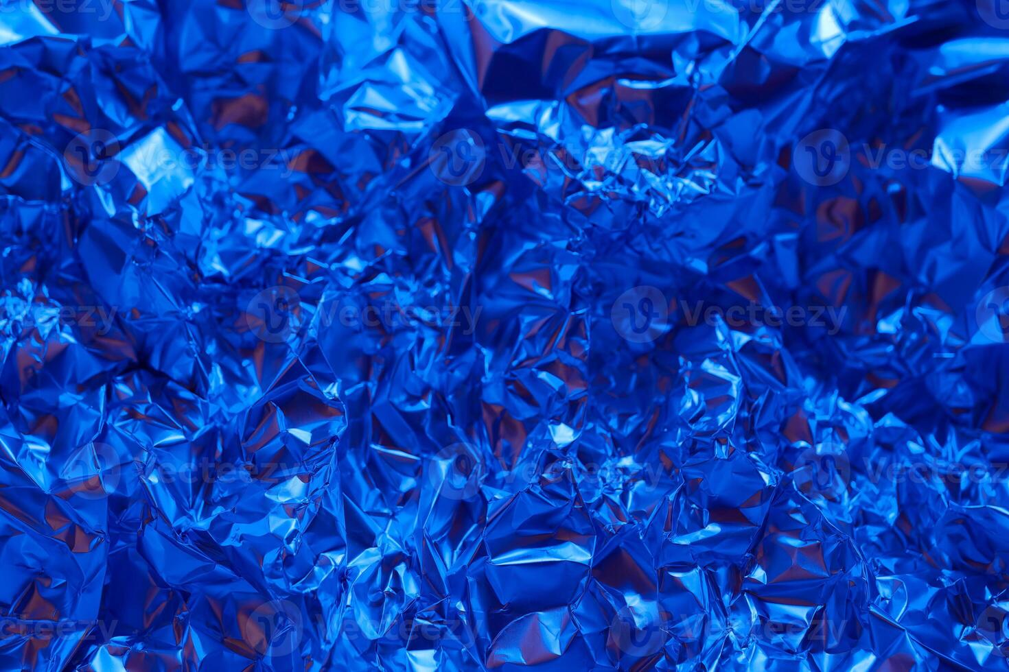 Bright blue crumpled aluminum foil creating an abstract textured background with a shiny surface reflecting light photo