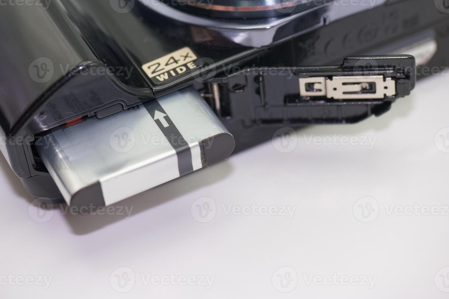 Close up view of a digital camera battery compartment showing battery insertion process photo