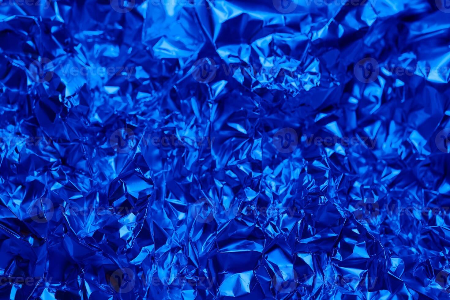 Crinkled blue foil texture in a close up view capturing light and shadows with a shiny surface effect photo
