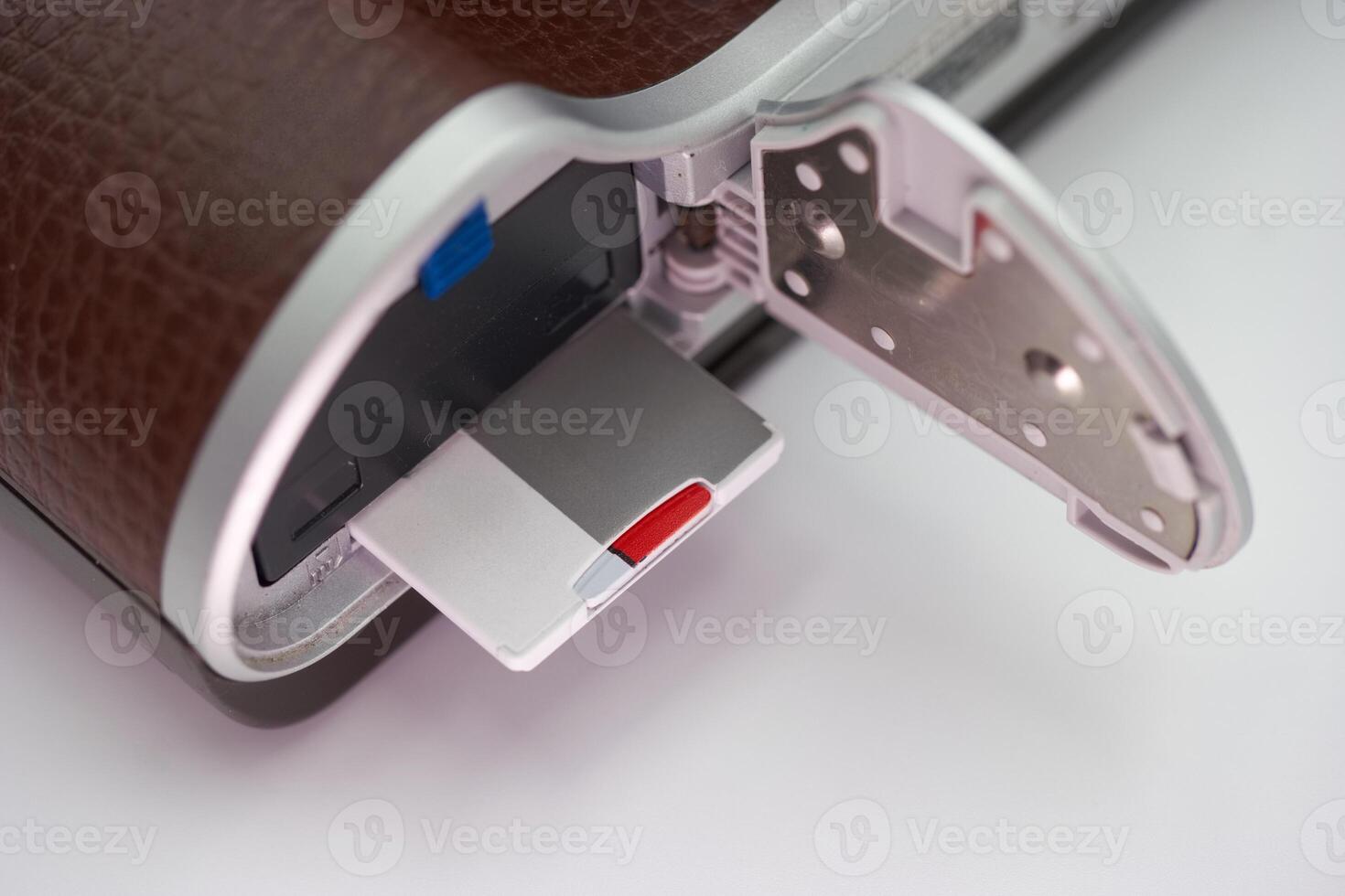Close up view of a camera revealing the memory card compartment with a silver and red memory card inserted photo