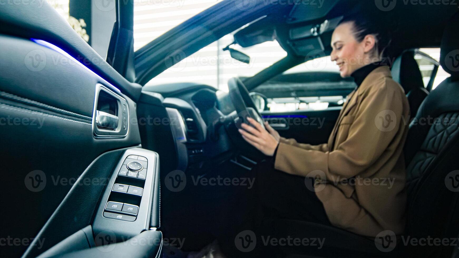 A satisfied, happy woman client sitting behind the wheel of a new car. Concept a joyful moment of car ownership, highlighting the excitement photo