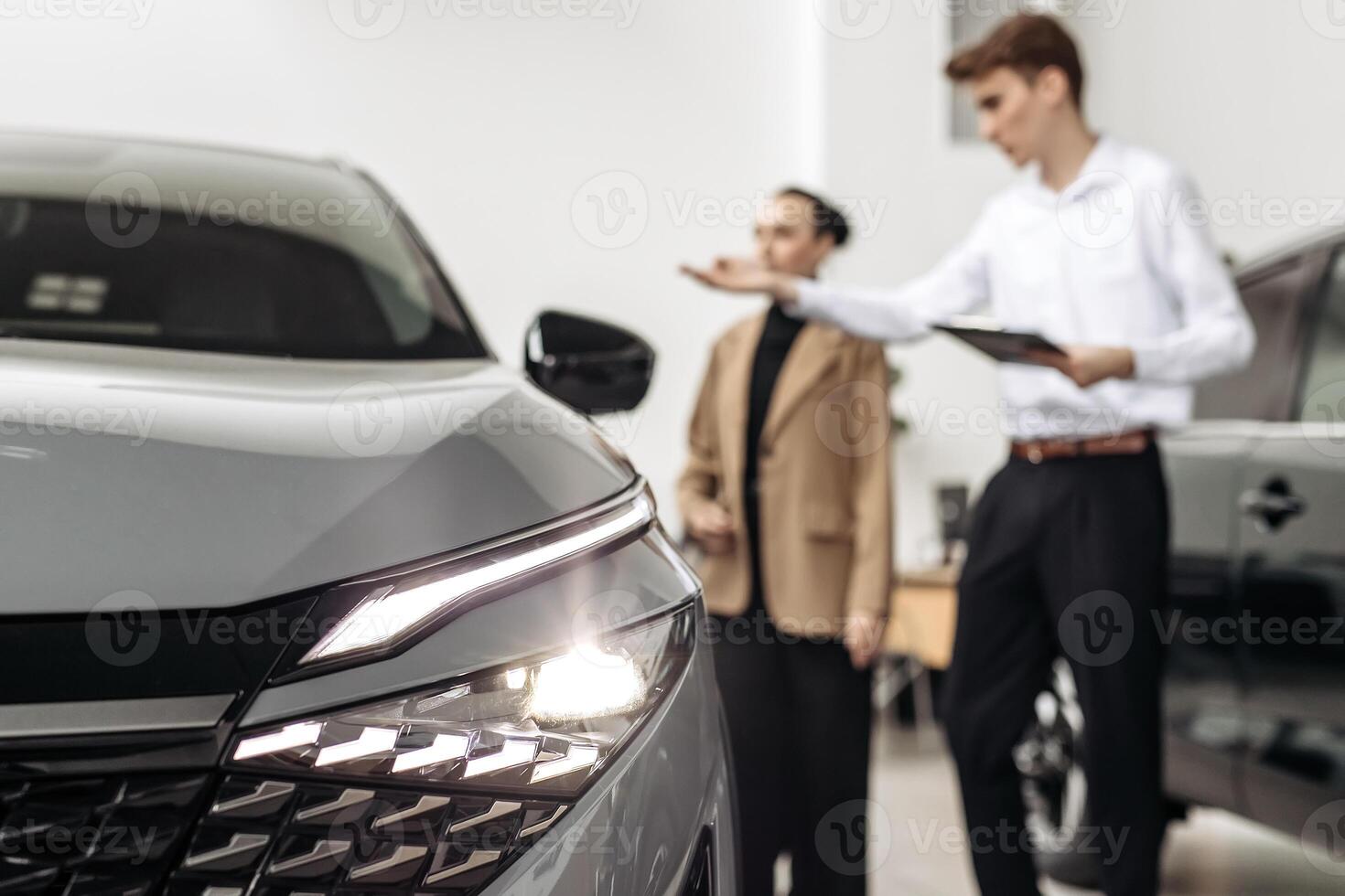 A car dealer advises a customer on the purchase or lease of a new car. The concept of an expensive purchase or lease of a modern car. photo