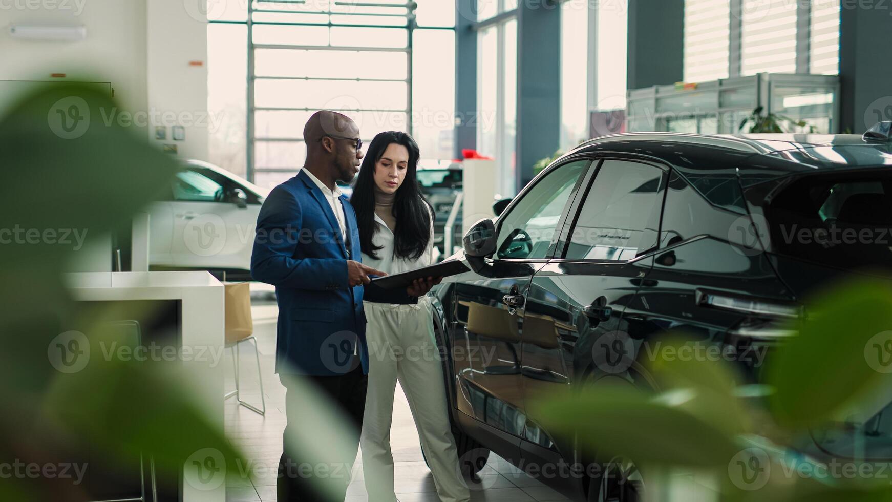 A car dealer advises a customer on the purchase or lease of a new car at a car dealership. The concept of an expensive purchase or lease of a modern car. photo