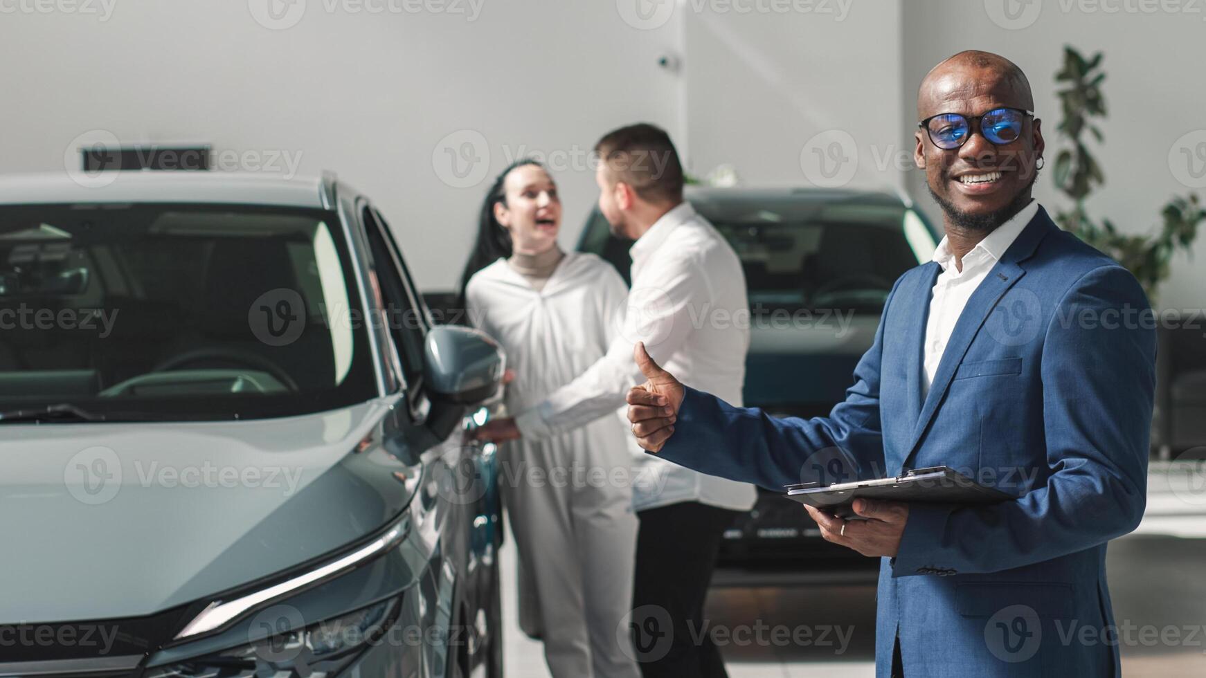 A happy young family gets the keys to their new car at a modern car dealership. The end of a test drive or purchase of a car photo