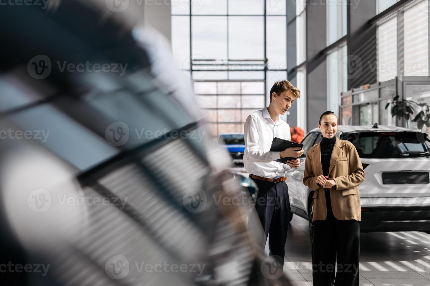 A car dealer in a modern car dealership advises a customer on buying or leasing a new car. The concept of an expensive purchase or lease of a modern car. photo