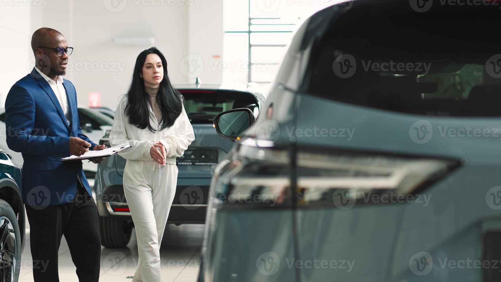 African-American dealer counseling a customer on buying a modern car at a car dealership. Concept of buying, leasing, test driving a new modern car. photo