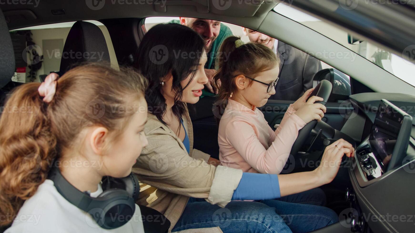 In a modern car dealership, a manager shows and advises a young family with children about buying or test driving a modern car. The concept of buying or leasing a new car photo