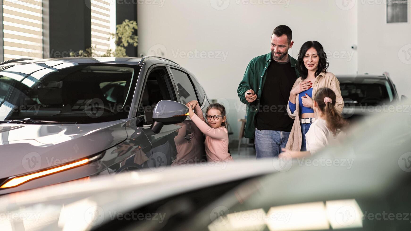 A happy young family gets the keys to their new car at a modern car dealership. The end of a test drive or purchase of a car. photo