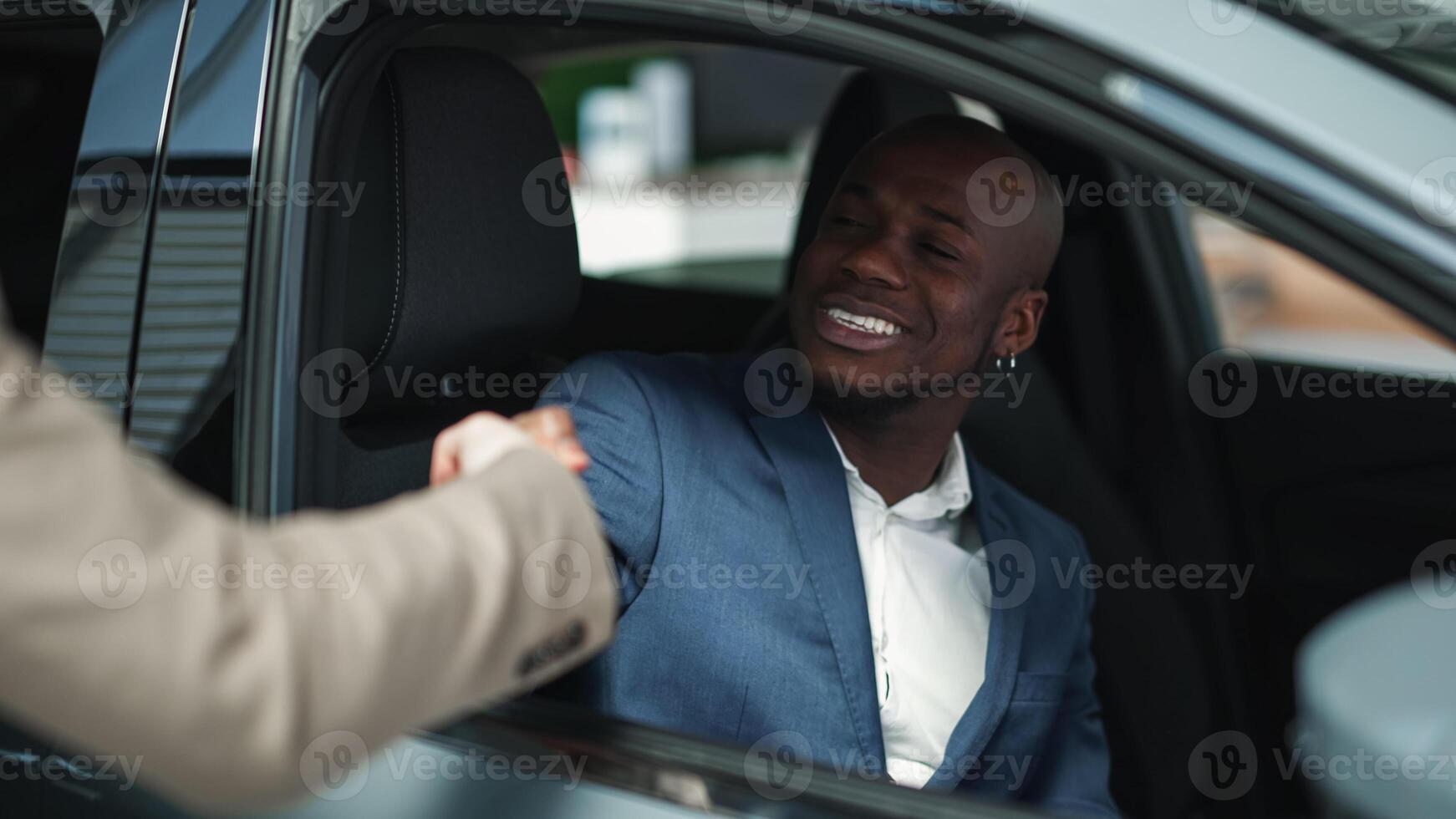 A car dealer in a modern car dealership advises an African-American customer on buying or leasing a new car. The concept of an expensive purchase or lease of a modern car photo