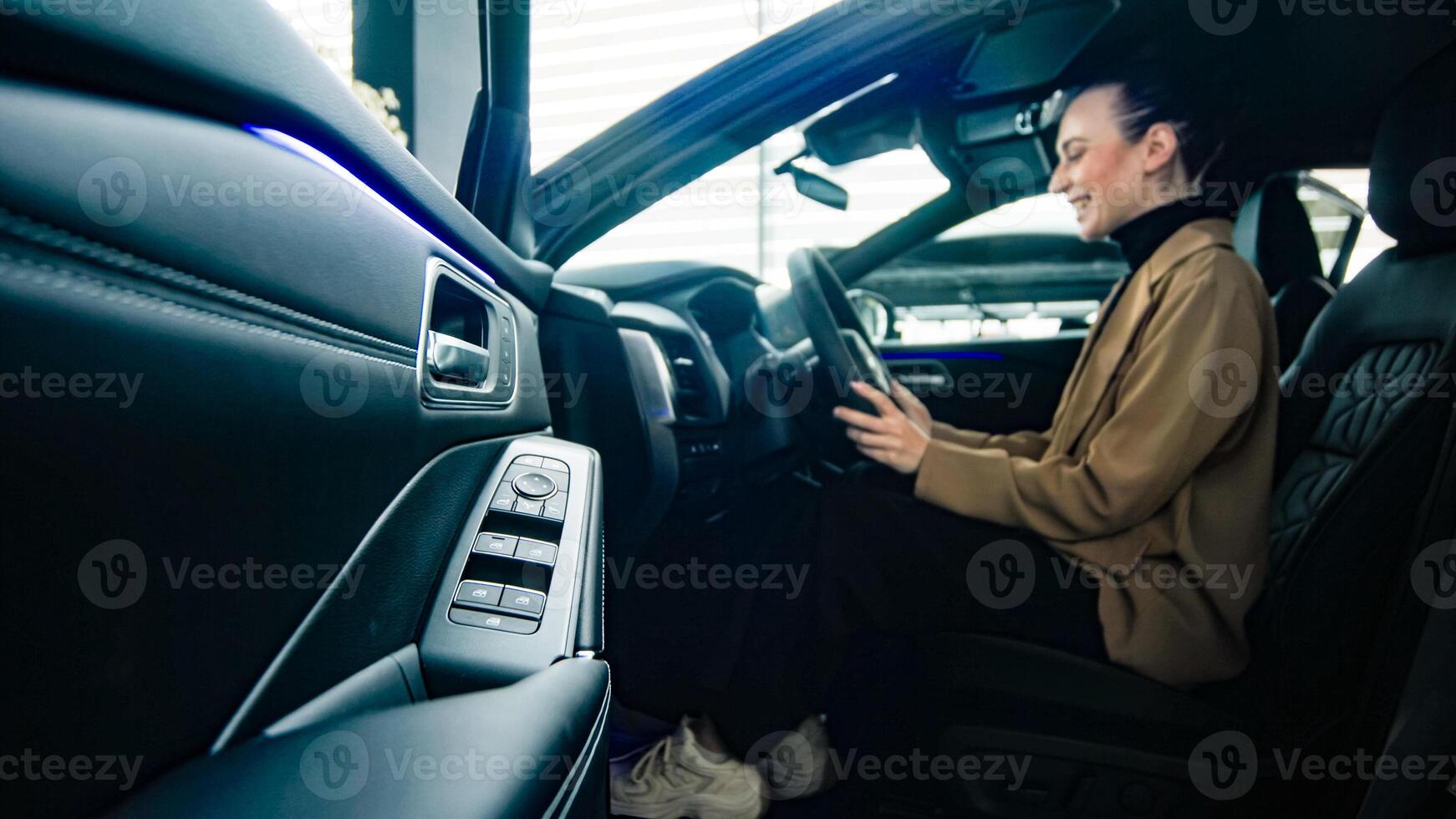 Business lady grips the steering wheel of a modern new car. Self-confidence and ambition are reflected in the choice of a new prestigious car. photo