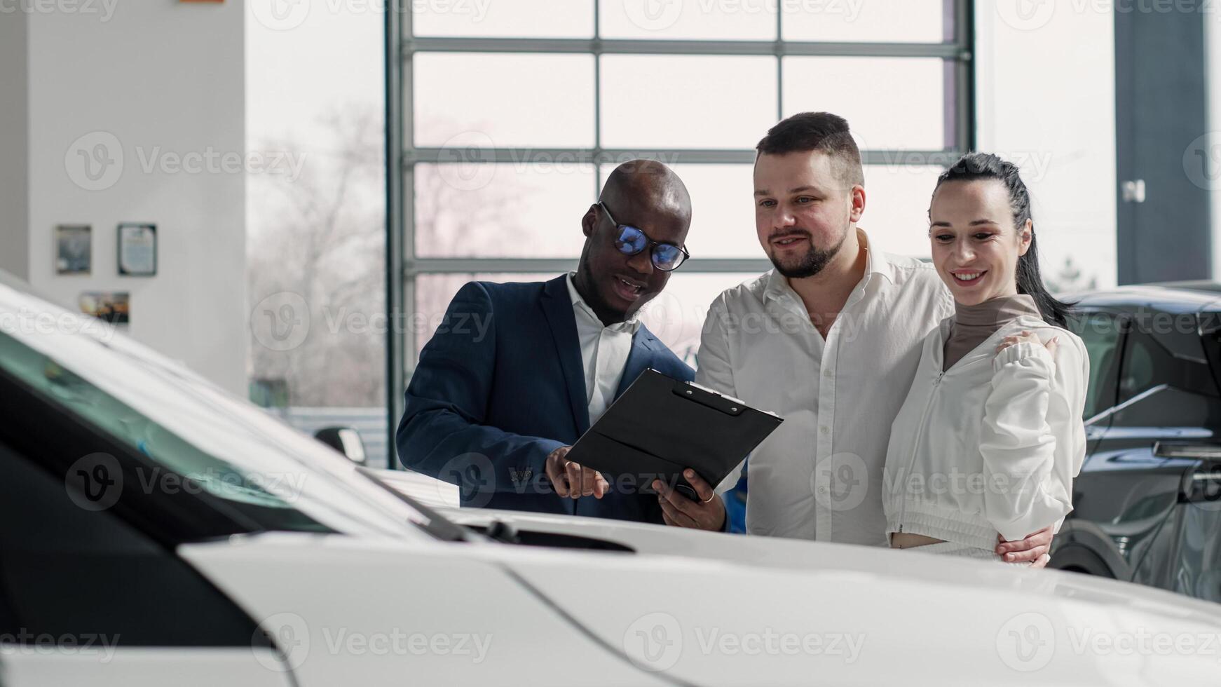 A happy young family in a modern car dealership after completing the purchase of a new family car. The concept of renting, test-driving a car photo