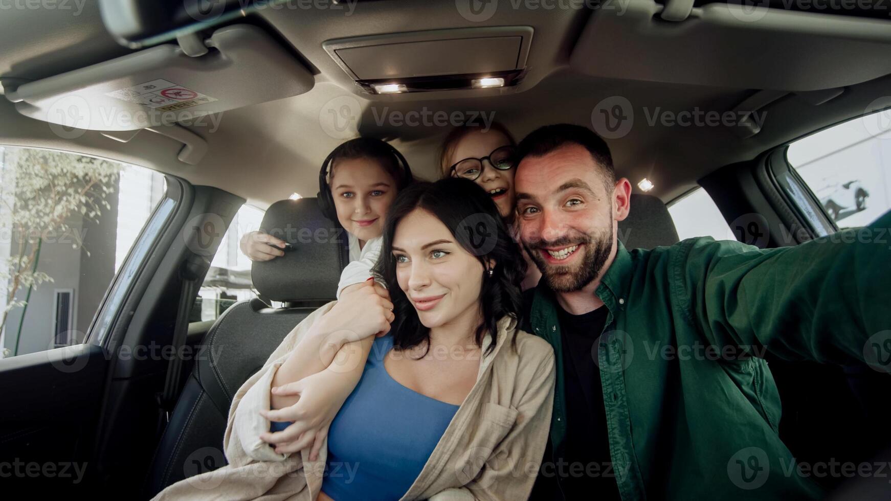 Husband makes a gift to a young wife with two daughters a new car in a modern car dealership. The concept of a successful purchase and happy family life. photo