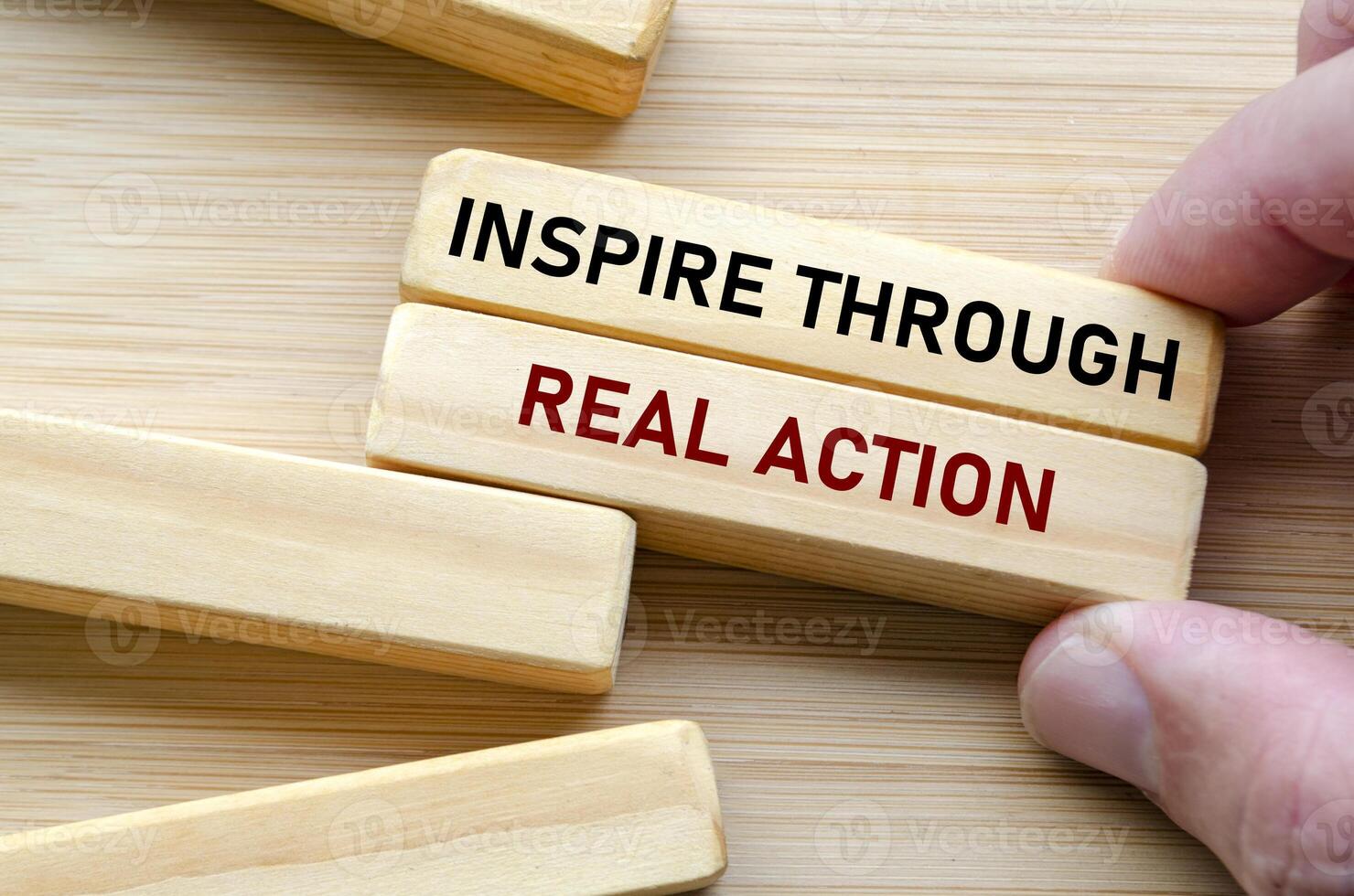 Inspire through real action message displayed on wood blocks, reflecting how true influence comes from doing rather than just speaking or commanding photo