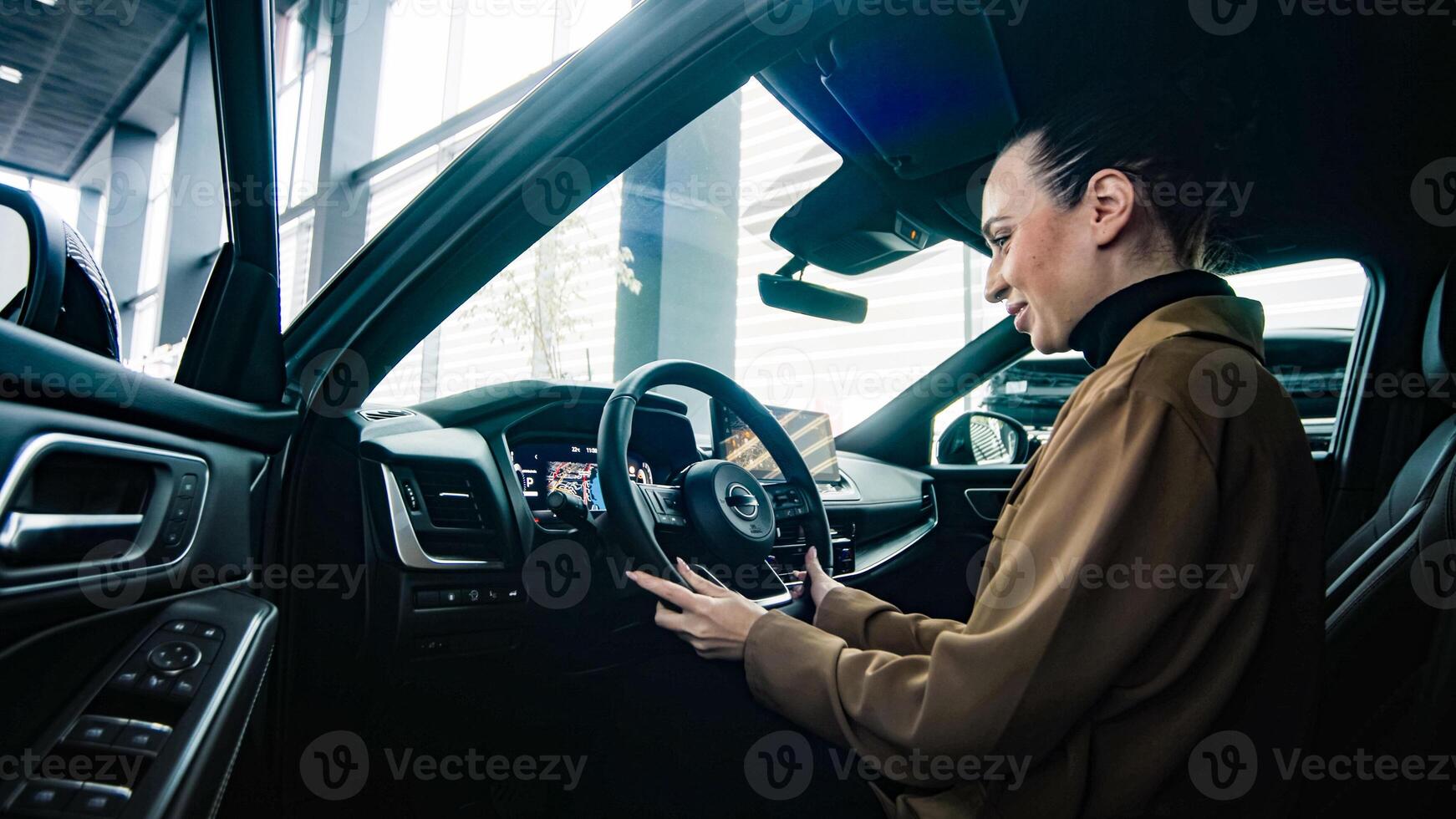 Self-confidence and ambition are reflected in the choice of a new prestigious car. Business lady grips the steering wheel of a modern new car. photo