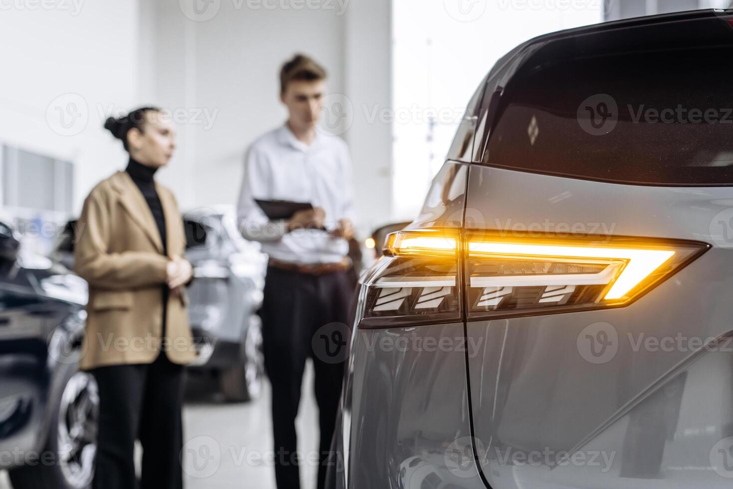 An African American dealer helps a customer choose a new car in a modern car dealership. The concept of buying, leasing, test driving and renting a car. photo