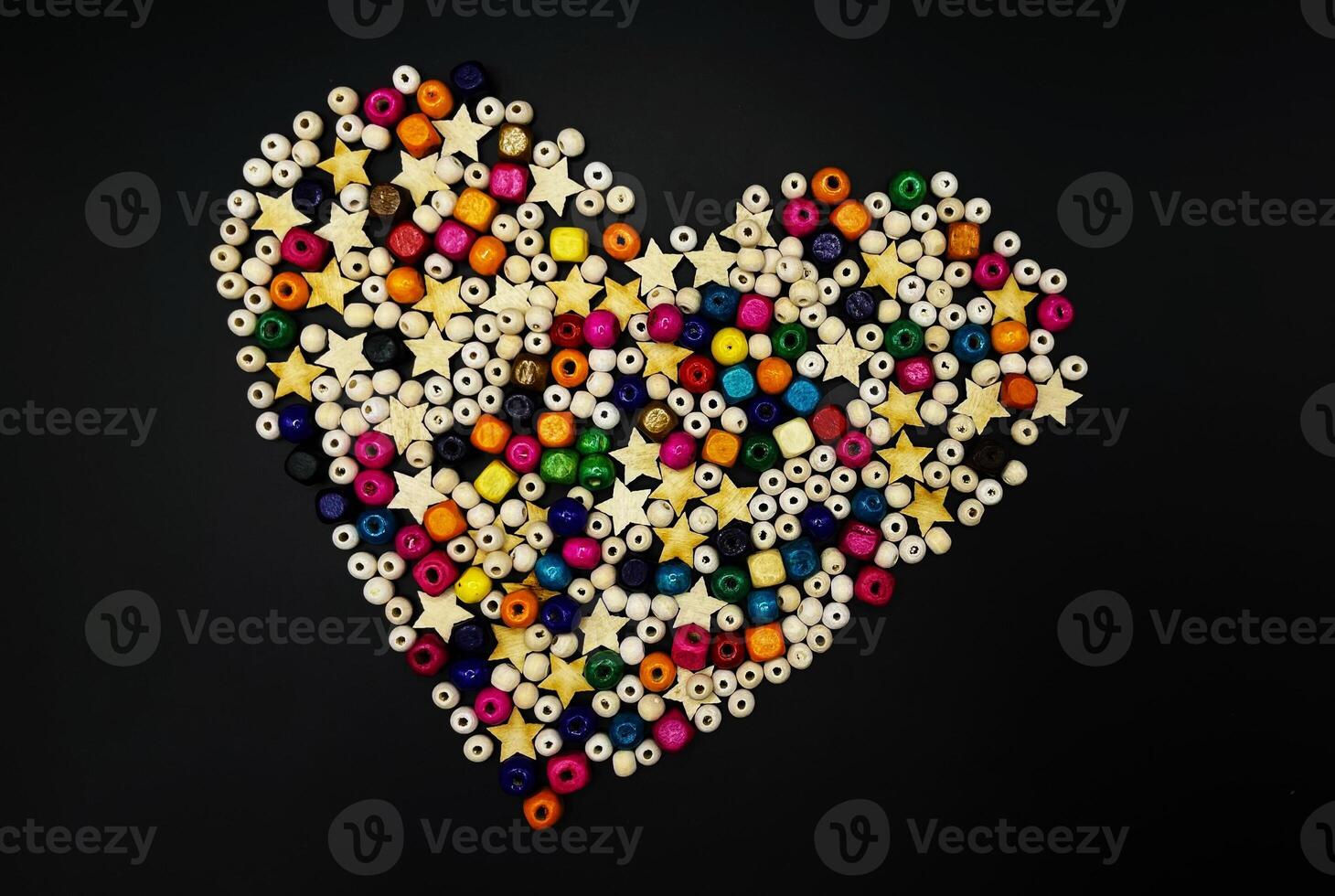 Wooden beads with colorful texture on a yellow background. A decorative accessory for handmade heart-shaped jewelry. A diverse concept of making handicrafts from natural materials. photo