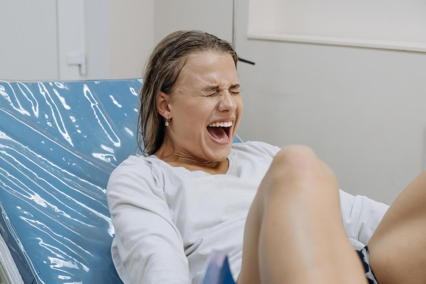 In a delivery room, a young woman is pushing during labor, face tense. Concept of birth effort. photo