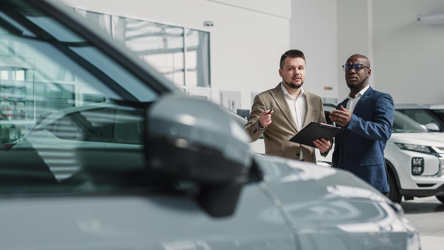 Car buying concept, expert, help and first-class service. Car sales manager shows a car to a customer in a car showroom. photo