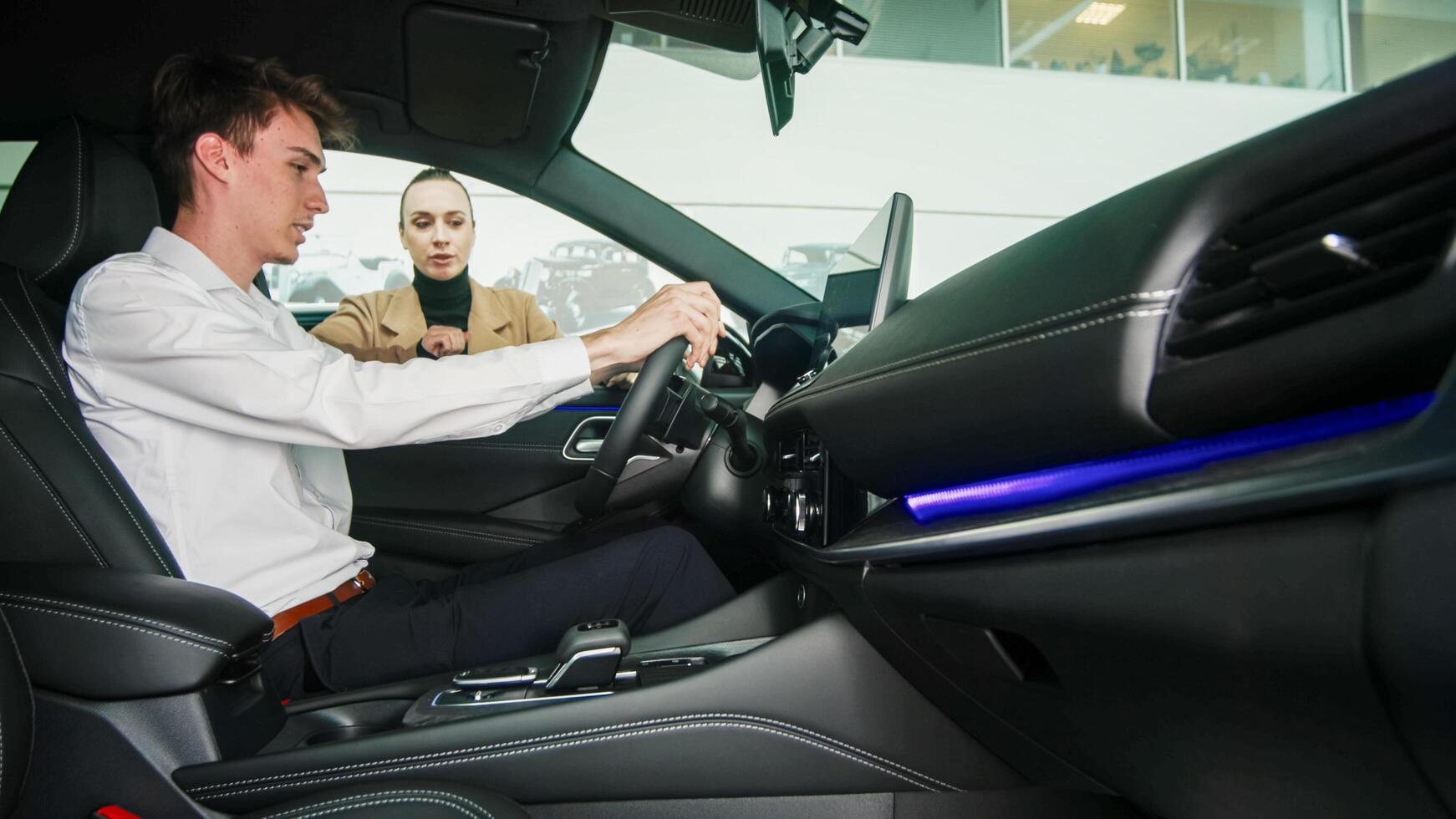 Car dealer showing a car to a customer in a showroom. Concept of purchase and assistance photo