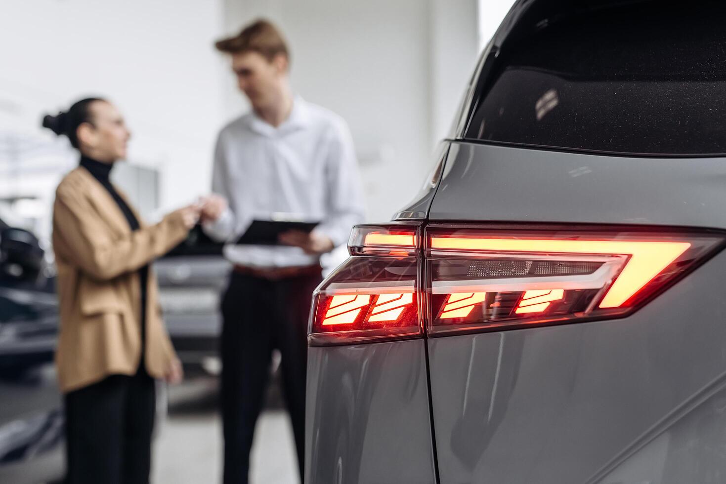 A dealer advises a client on purchasing a modern car at a car dealership. The concept of purchasing, renting and test-driving a new car photo