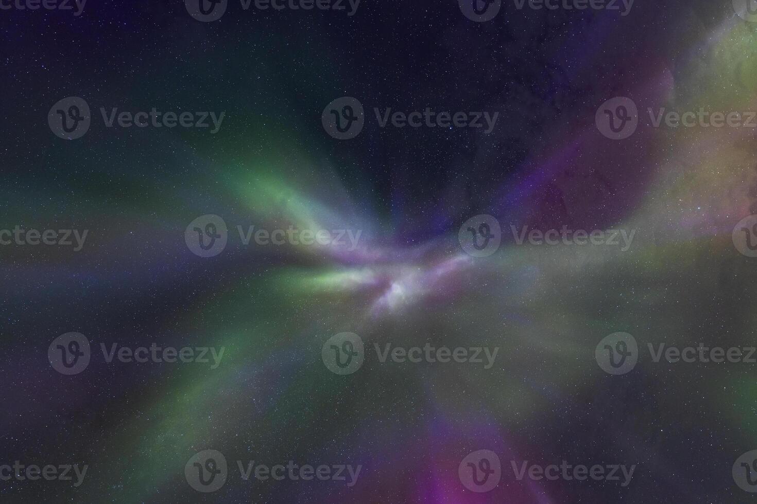 Emerald aurora arcs across the night sky reflecting faintly in the meandering waterway below. photo